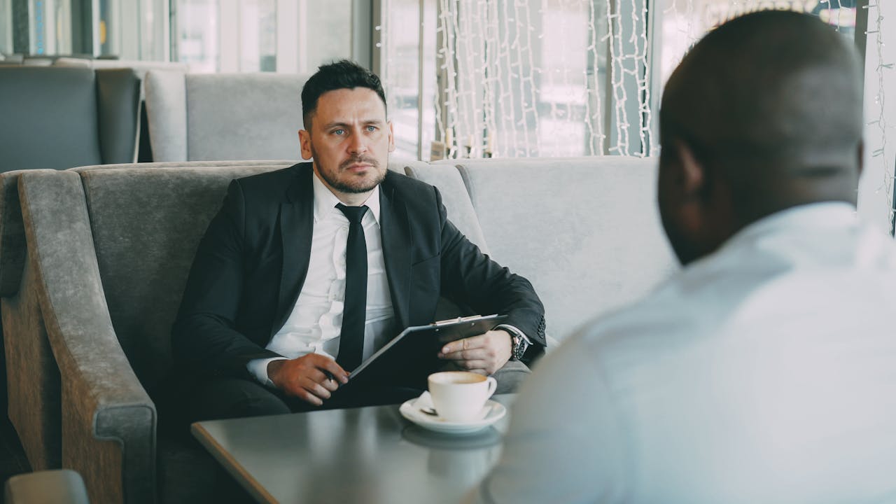 home-services-02 Two businessmen having a serious conversation over coffee in a stylish cafe setting.